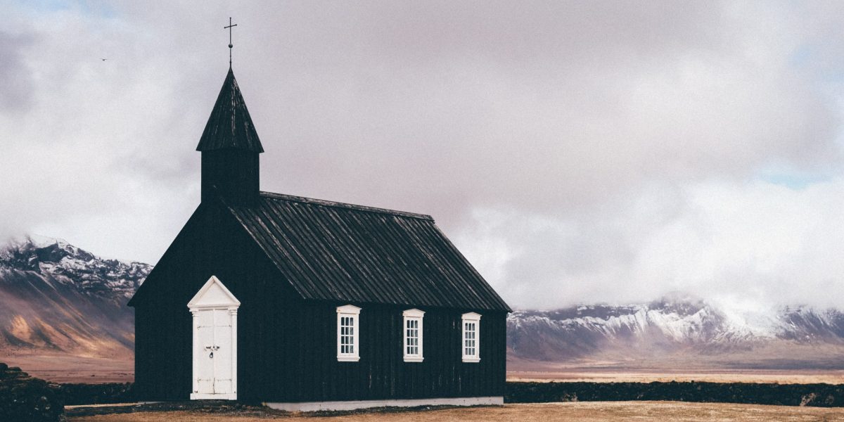 black and white church near open field background of mountain view